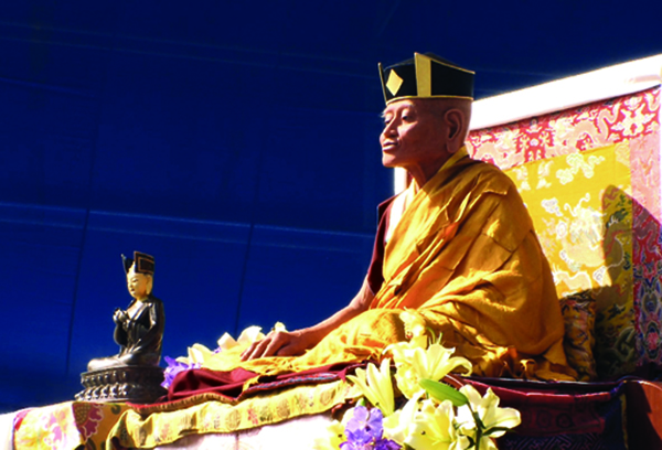 Cette statue grandeur nature du Ier Karmapa fut réalisée sous la direction artistique directe du XVIIe Karmapa, dans le but de présenter un portrait fidèle. On la voit ici sur l’estrade, lors de la cérémonie d’ouverture des célébrations de ‘Karmapa 900’, à Bodhgaya en Inde, en 2010. Photo : avec l’aimable autorisation de Maia Saabye Christensen.